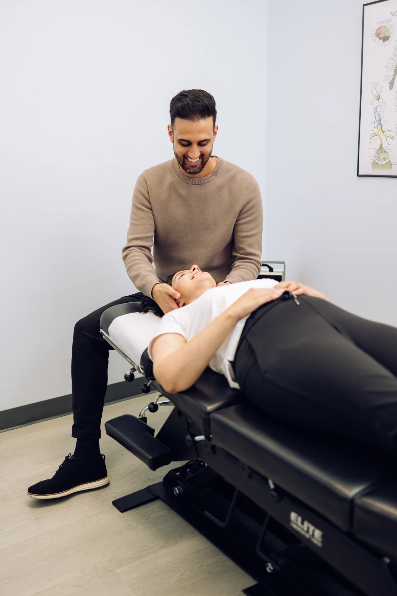 A chiropractor adjusts a patient lying on a treatment table in a clinic setting.