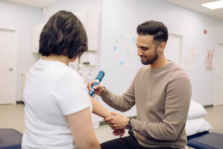 A man uses a medical device on a woman's forearm in a clinic setting.